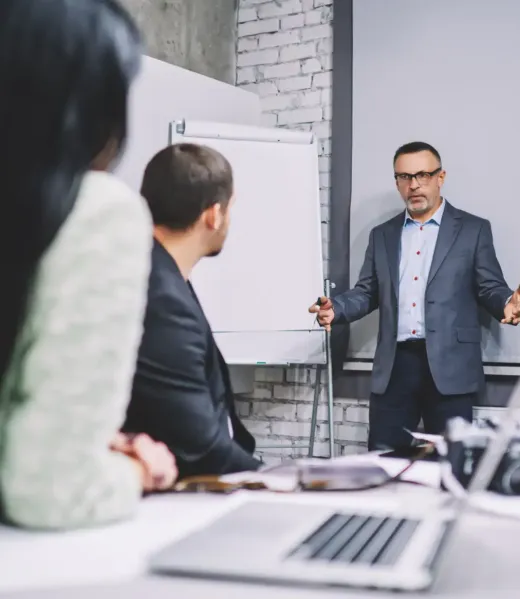 Professional economist talking near flipchart explaining information for business project, successful business people collaborating together discussing mentoring during seminar presentation in company